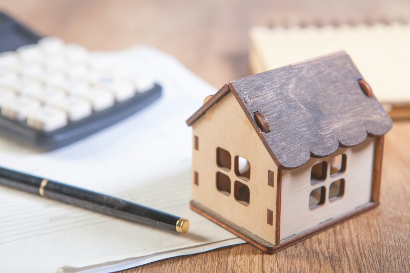 Model house with calculator and pen on desk